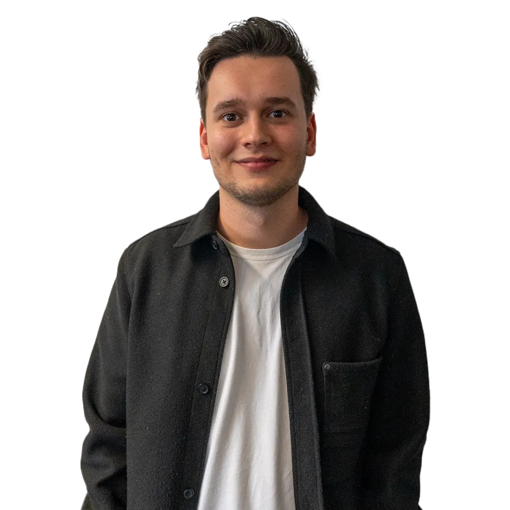 Jonge man met kort donker haar, gekleed in een zwarte overshirt en wit T-shirt, staat rechtop en kijkt glimlachend in de camera tegen een transparante achtergrond.