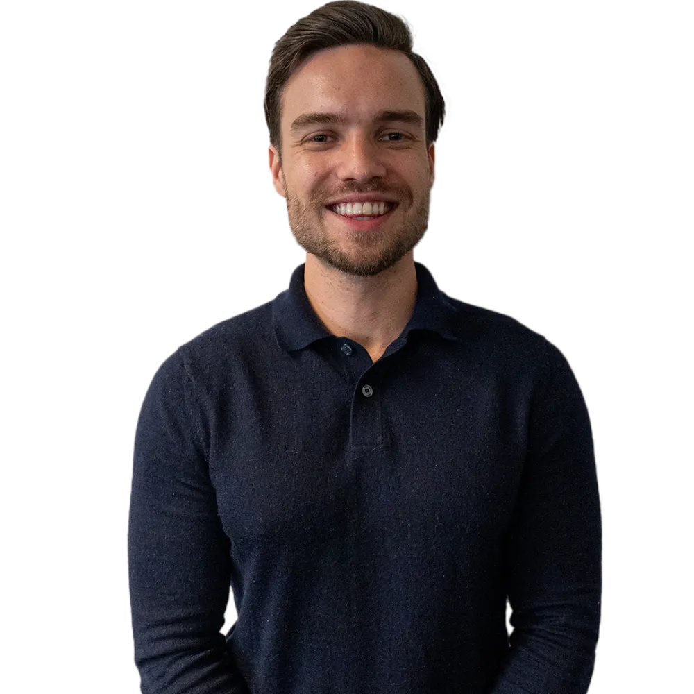 Jonge man met kort donker haar, gekleed in een zwarte overshirt en wit T-shirt, staat rechtop en kijkt glimlachend in de camera tegen een transparante achtergrond.